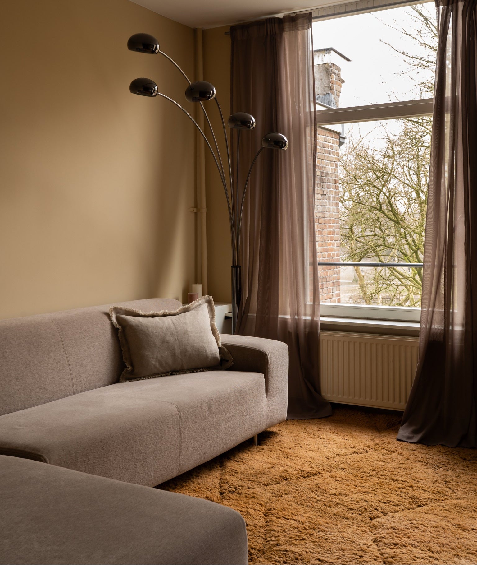 Living room with a gray sofa, floor lamp, and large window with curtains.